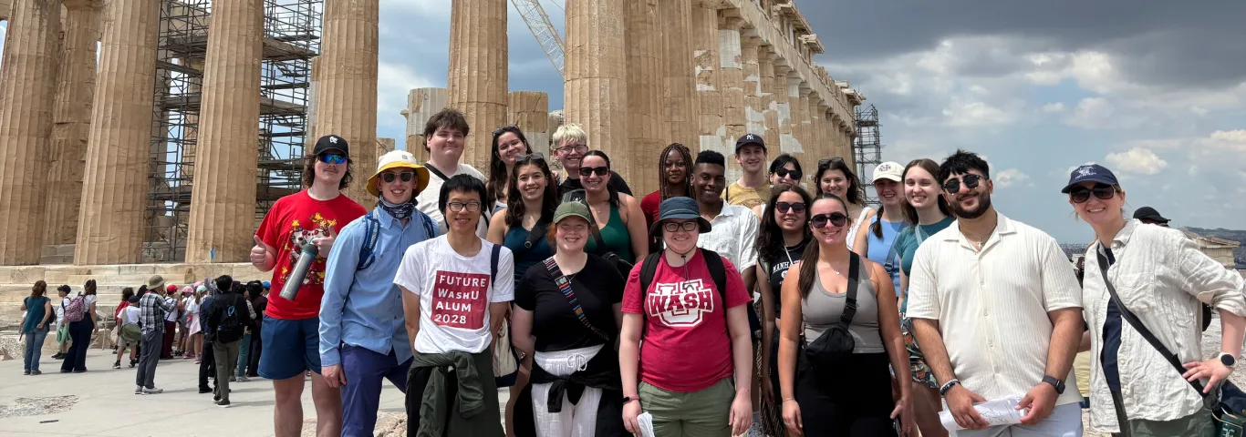  a group of students standing in front of the Greek ruins
