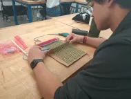 student weaving on a small cardboard loom