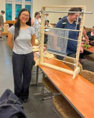 student standing next to handmade loom