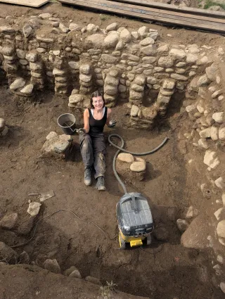 Spanger sitting in a archaeological site surrounded by stones and tools