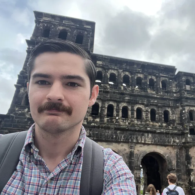 Holden in front of aged structure with arched windows