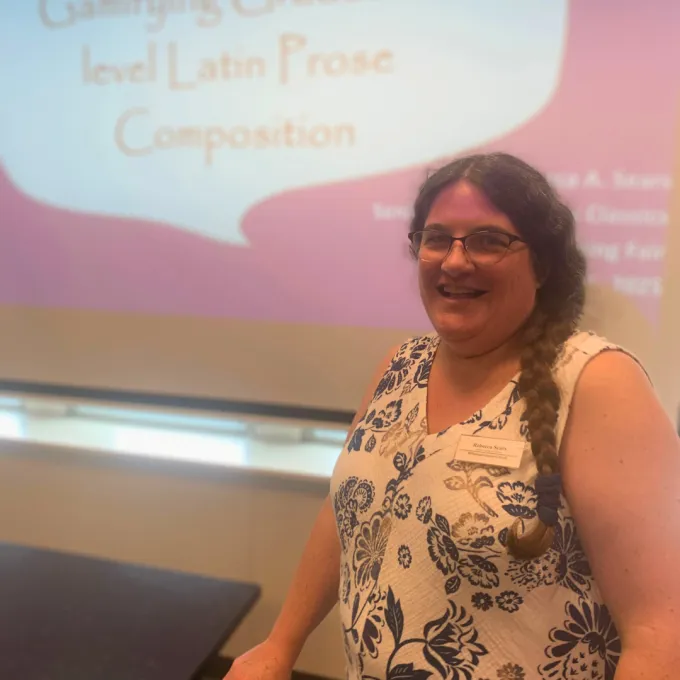 Sears standing in front of a screen with a slide that reads "Gamifying Graduate-level Latin Prose Composition"