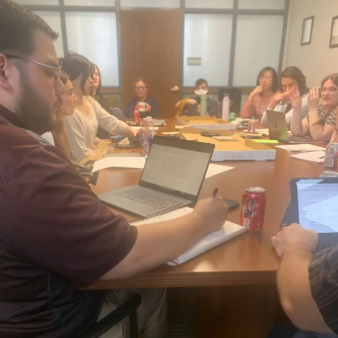Classics student taking notes in a feedback session faculty and peers