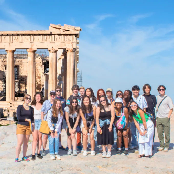 a group of students standing in front of Greek columns